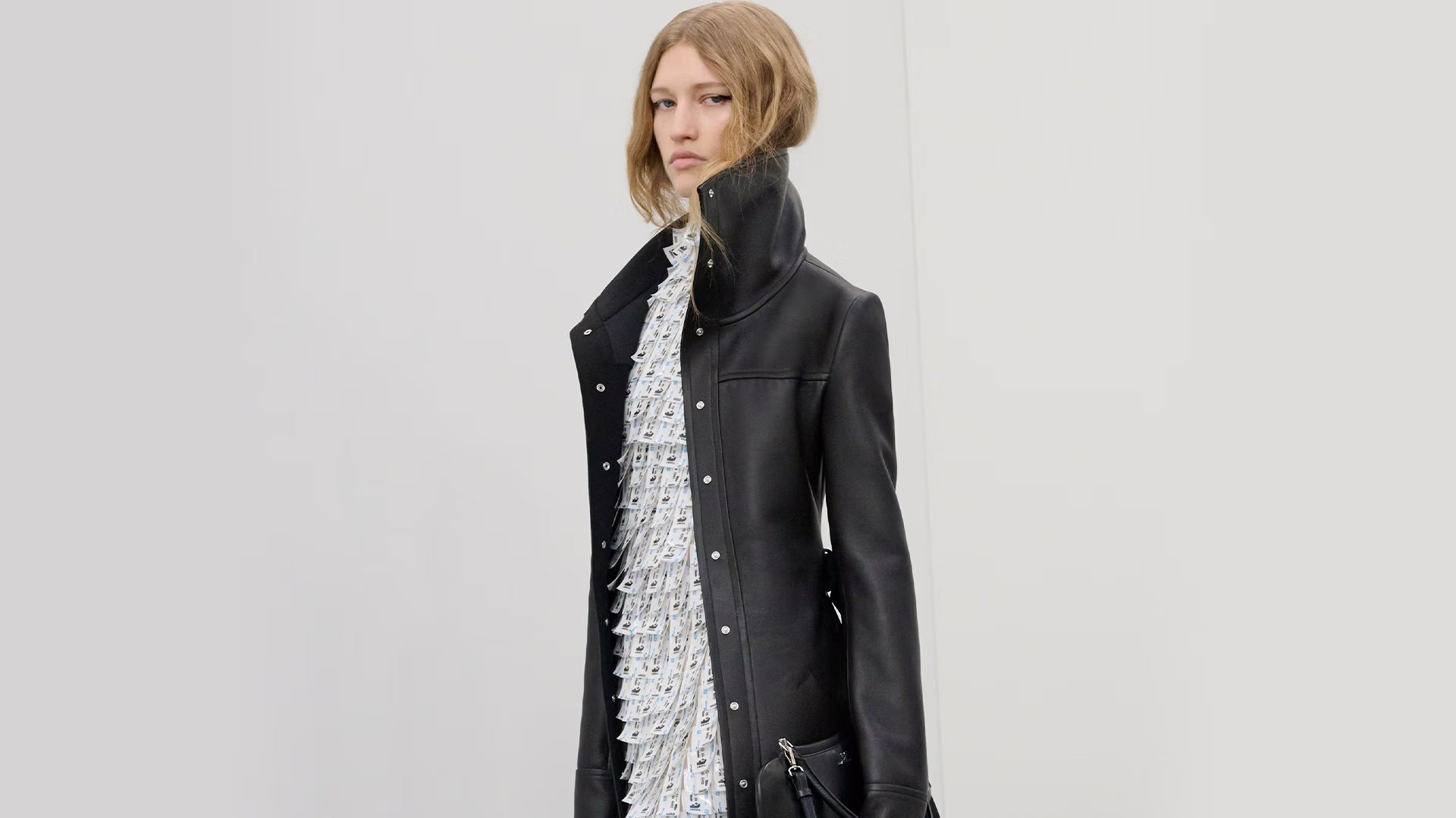 דוגמנית צועדת על מסלול רחוב סוריאליסטי בפריז, לבושה במראה לבן, במהלך תצוגת קולקציית סתיו/חורף 2026 של מותג האופנה קוראז' (Courrèges).